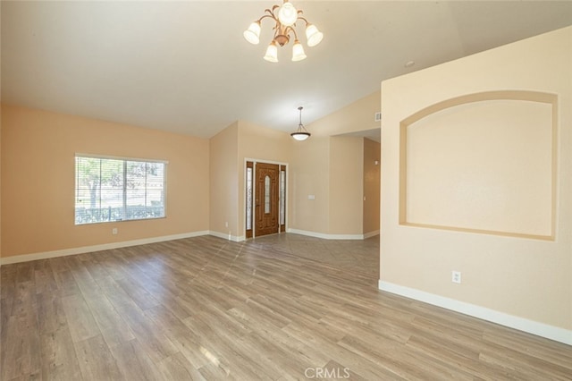 unfurnished room featuring vaulted ceiling, an inviting chandelier, and light wood-type flooring