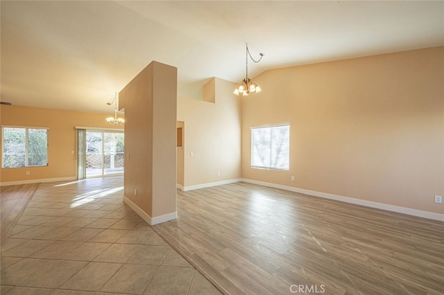 spare room with light hardwood / wood-style floors, lofted ceiling, and a notable chandelier