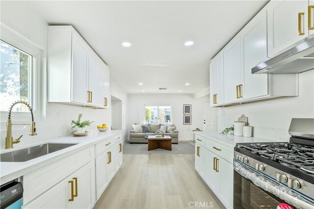 kitchen with sink, white cabinets, black dishwasher, and stainless steel range with gas stovetop