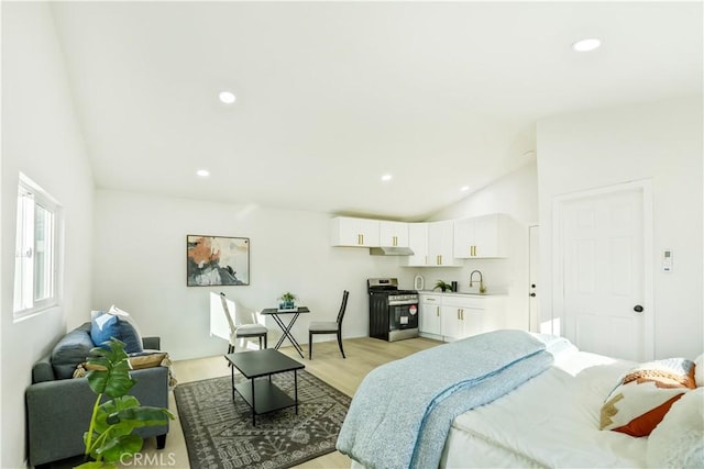 bedroom with vaulted ceiling, light wood-type flooring, and sink