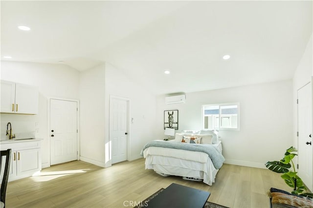 bedroom featuring light wood-type flooring, sink, lofted ceiling, and a wall mounted air conditioner