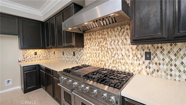 kitchen featuring range with two ovens, crown molding, wall chimney exhaust hood, and tasteful backsplash