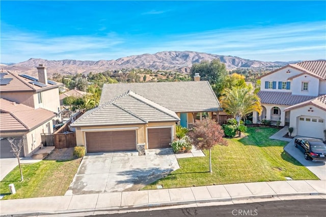 view of front of property featuring a front yard, a garage, and a mountain view