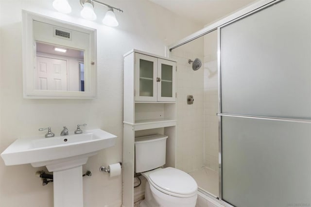 bathroom featuring toilet and a shower with door