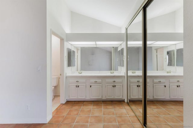 bathroom featuring tile patterned flooring, toilet, vanity, and vaulted ceiling