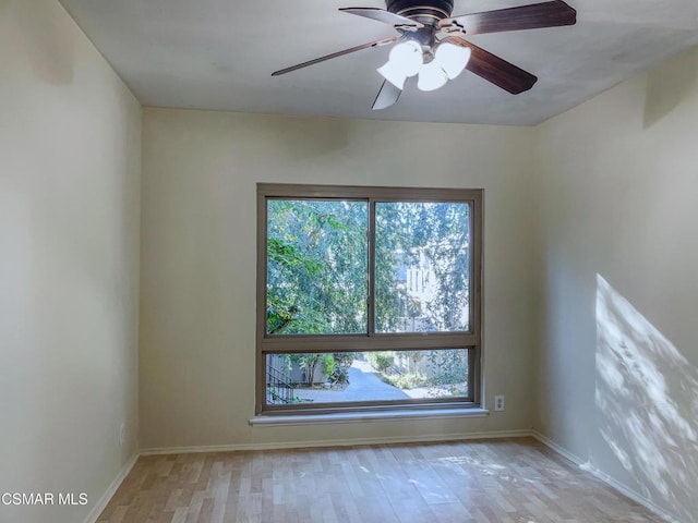 empty room with ceiling fan, a healthy amount of sunlight, and light hardwood / wood-style flooring