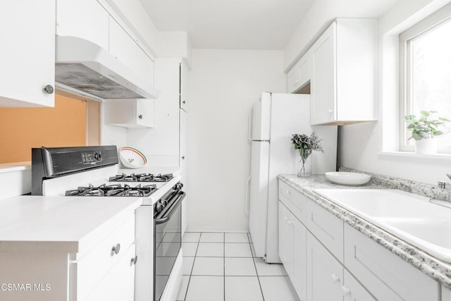 kitchen featuring light tile patterned floors, custom exhaust hood, white cabinetry, range with gas stovetop, and sink