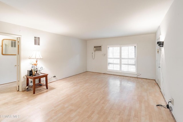 empty room with light hardwood / wood-style floors and a wall mounted air conditioner