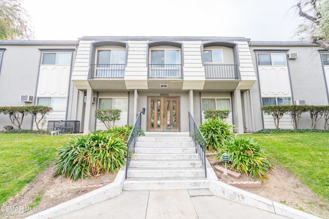 view of front of property with a front yard, french doors, and a balcony