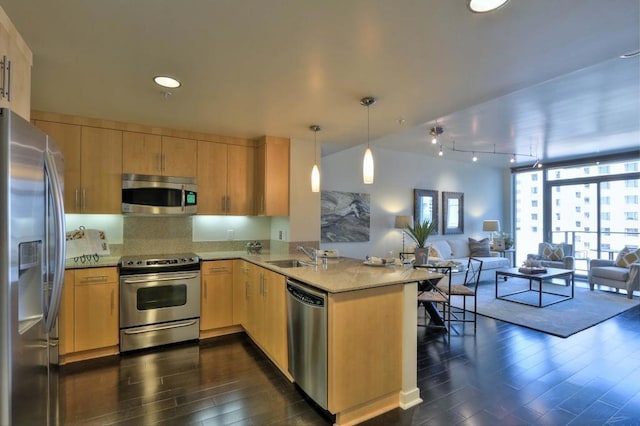 kitchen featuring sink, appliances with stainless steel finishes, dark hardwood / wood-style flooring, decorative light fixtures, and kitchen peninsula