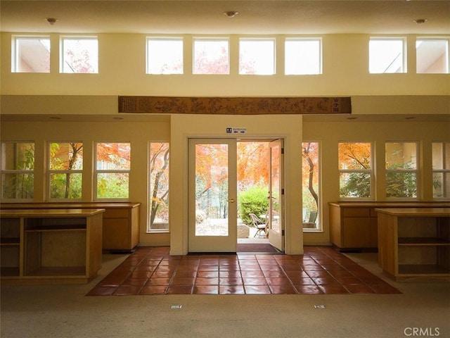 doorway to outside with a high ceiling, dark tile patterned flooring, and french doors