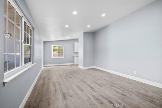 unfurnished living room featuring vaulted ceiling and light hardwood / wood-style floors