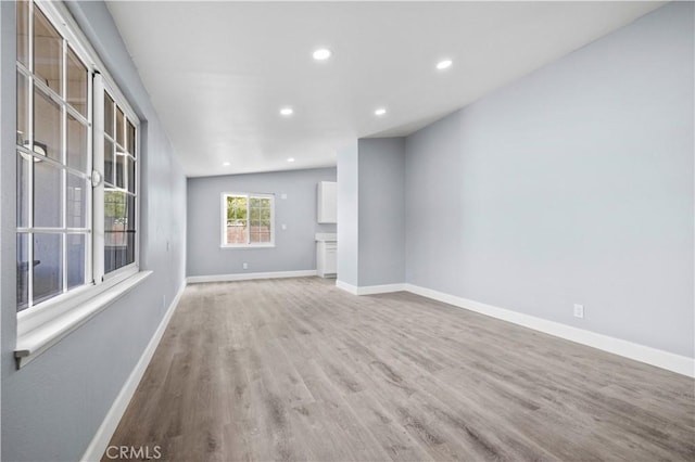 unfurnished living room with lofted ceiling and light wood-type flooring