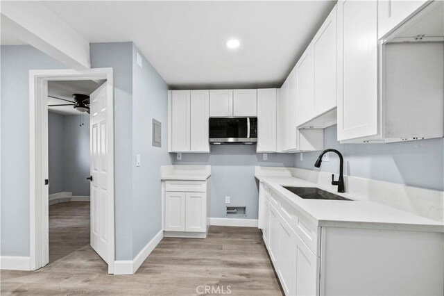 kitchen featuring ceiling fan, white cabinets, sink, and light hardwood / wood-style flooring