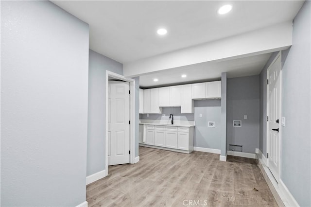 kitchen with light hardwood / wood-style floors, sink, and white cabinetry