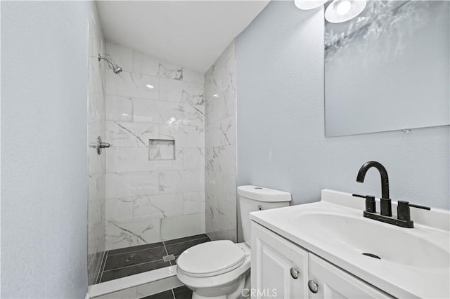 bathroom with toilet, tile patterned flooring, a tile shower, and vanity