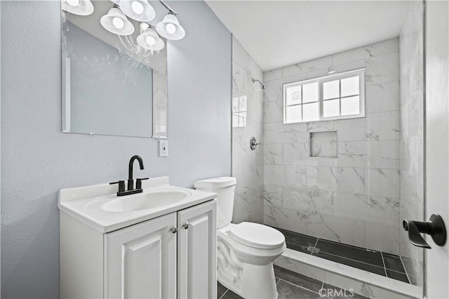 bathroom with toilet, vanity, and a tile shower