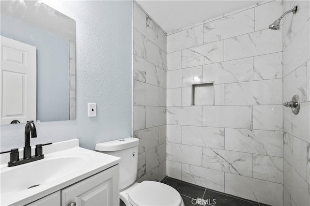 bathroom with vanity, toilet, and tiled shower