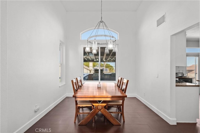 dining space with dark wood-type flooring, a high ceiling, and a notable chandelier