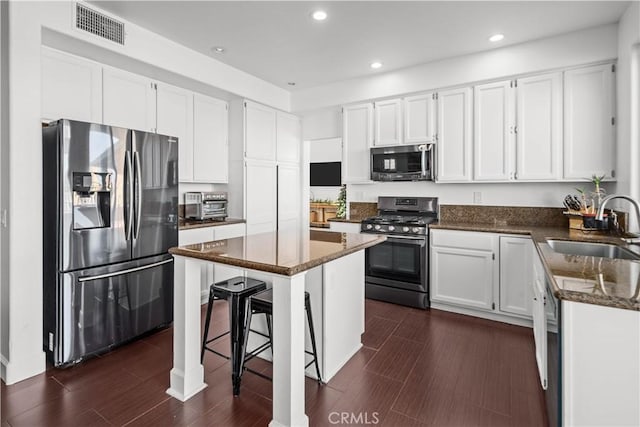 kitchen featuring white cabinetry, a breakfast bar area, appliances with stainless steel finishes, a kitchen island, and sink