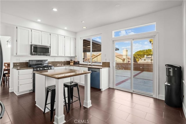 kitchen featuring stainless steel appliances, a center island, white cabinets, a breakfast bar, and sink