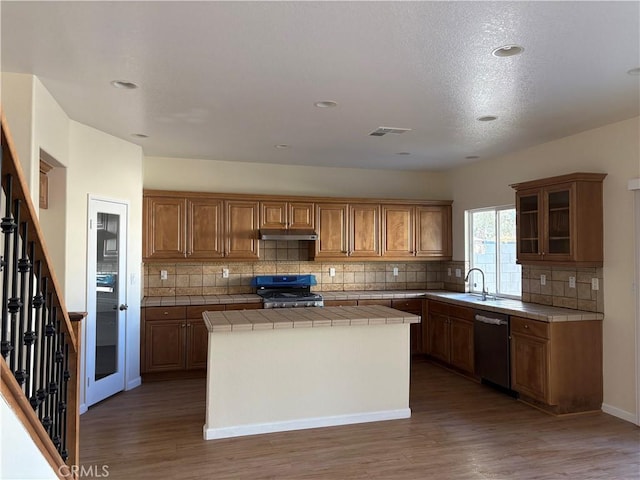 kitchen featuring black range oven, dark wood-type flooring, stainless steel dishwasher, tile countertops, and a kitchen island