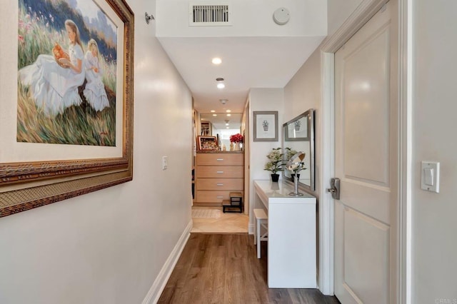 hall with dark wood-style floors, baseboards, and visible vents