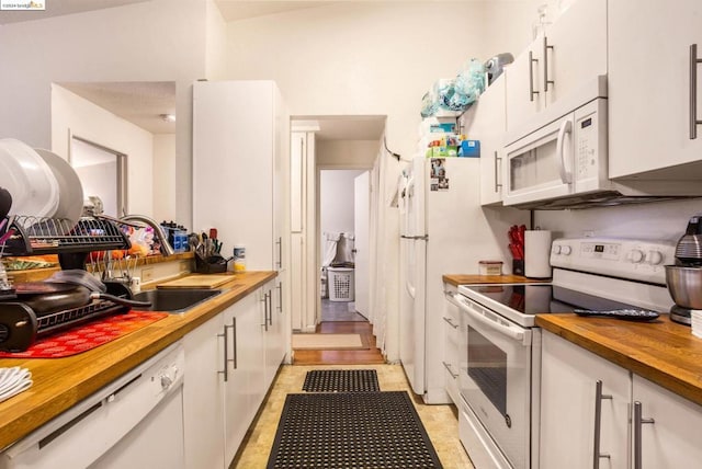 kitchen with wooden counters, sink, white appliances, and white cabinetry