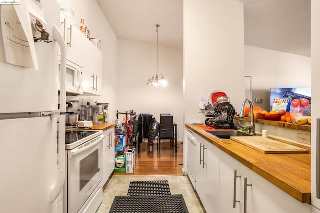 kitchen with an inviting chandelier, white appliances, hanging light fixtures, white cabinets, and sink