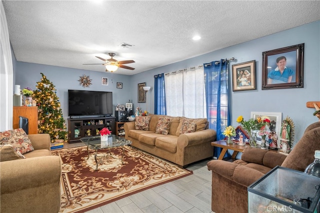 living room with ceiling fan and a textured ceiling