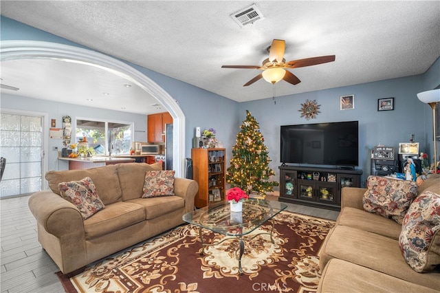 living room with ceiling fan and a textured ceiling