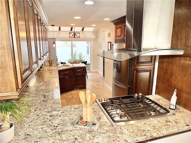 kitchen with kitchen peninsula, decorative light fixtures, stainless steel gas cooktop, light stone countertops, and range hood