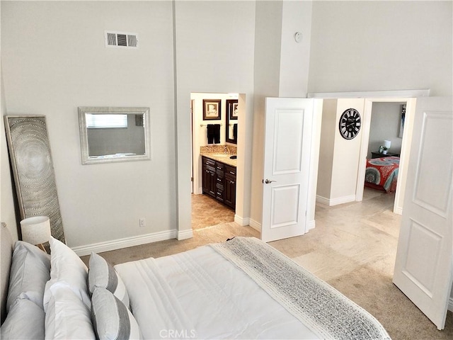 carpeted bedroom featuring ensuite bathroom and a high ceiling