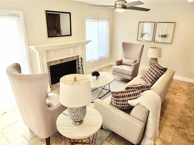 living area featuring ceiling fan, plenty of natural light, and a fireplace