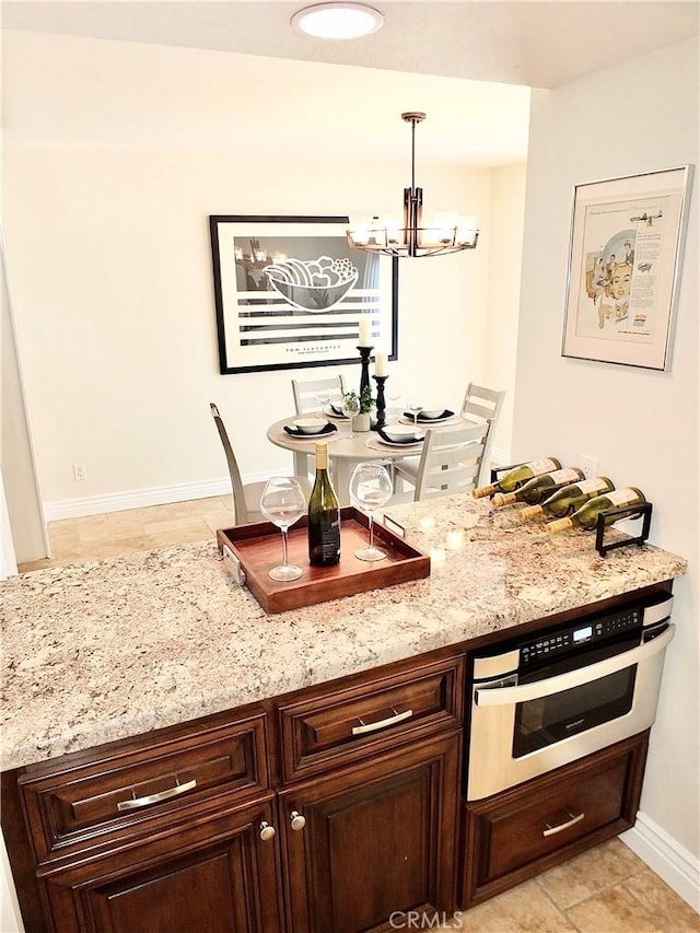 kitchen featuring stainless steel oven, hanging light fixtures, dark brown cabinets, and a chandelier