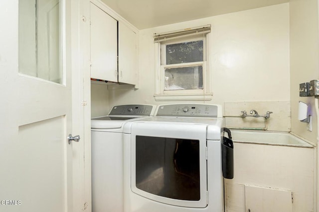 clothes washing area with cabinets and separate washer and dryer