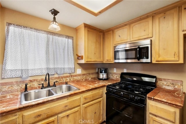 kitchen featuring black gas range, decorative light fixtures, light brown cabinets, and sink