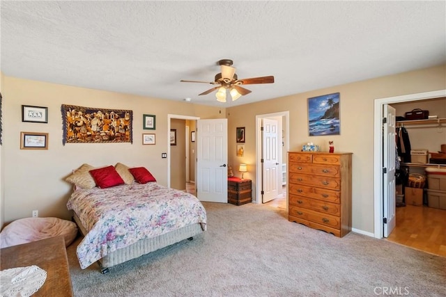 carpeted bedroom with a spacious closet, ceiling fan, a closet, and a textured ceiling