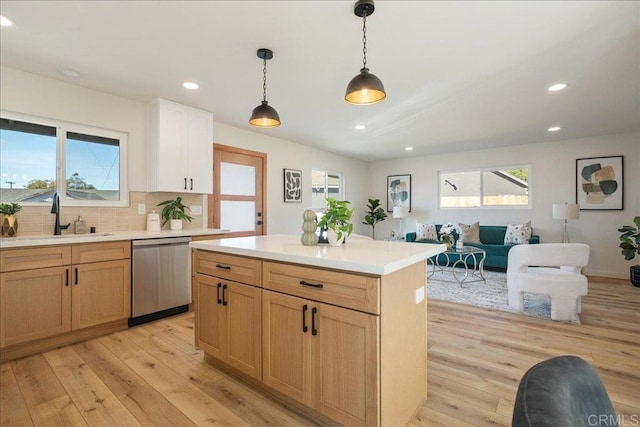 kitchen featuring pendant lighting, a kitchen island, light hardwood / wood-style floors, sink, and stainless steel dishwasher