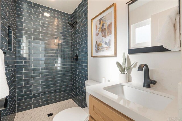 bathroom featuring toilet, vanity, and tiled shower