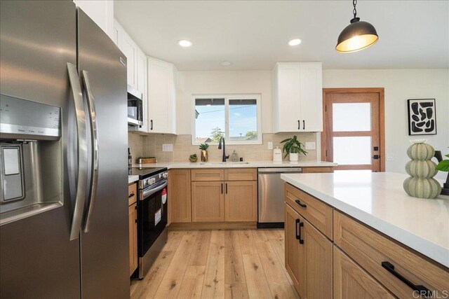 kitchen with white cabinetry, stainless steel appliances, tasteful backsplash, pendant lighting, and sink