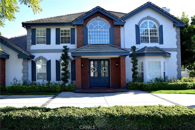 view of front of house with a tiled roof, french doors, and stucco siding