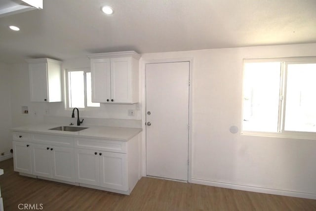 kitchen with wood-type flooring, sink, and white cabinetry