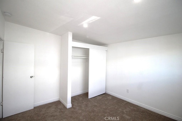 unfurnished bedroom featuring a closet and dark colored carpet