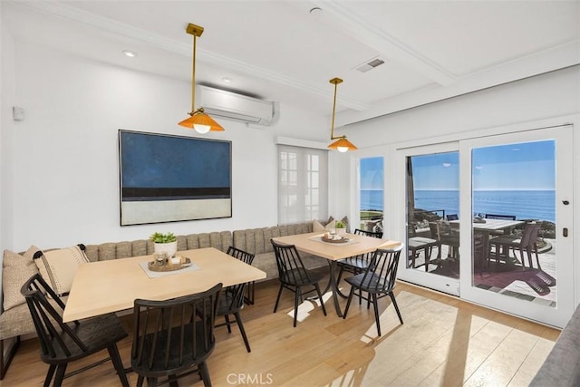 dining space featuring an AC wall unit, light wood-type flooring, breakfast area, a water view, and beam ceiling