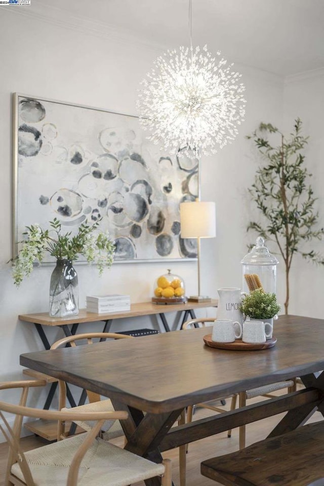 dining space featuring hardwood / wood-style flooring, ornamental molding, and a notable chandelier