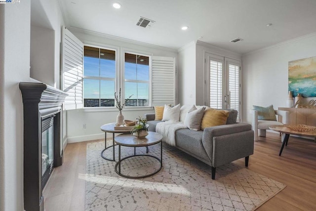 living room with light hardwood / wood-style floors, ornamental molding, and french doors