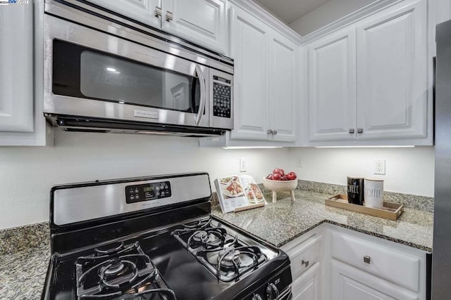 kitchen with range with gas stovetop, white cabinets, and light stone countertops