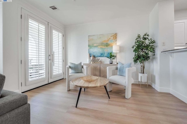 sitting room featuring crown molding, light hardwood / wood-style floors, and french doors