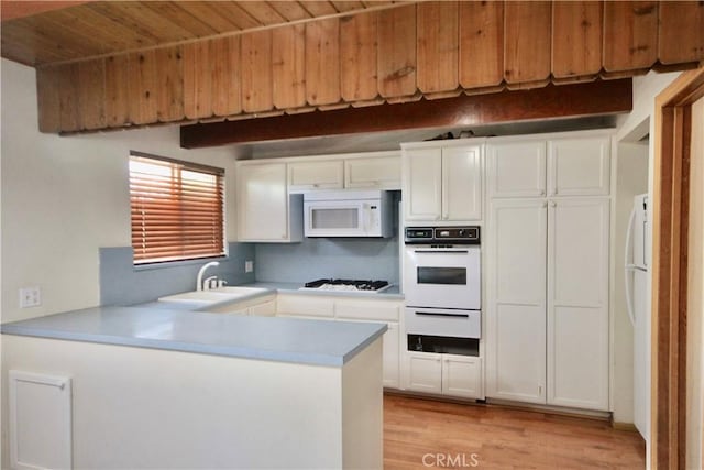 kitchen featuring kitchen peninsula, sink, white appliances, white cabinetry, and light wood-type flooring